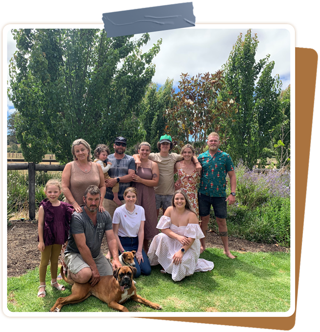 Family of nine posing outdoors with their Boxer dog on the lawn